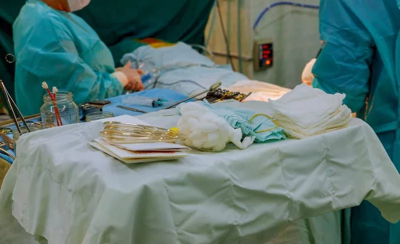 Surgical team performing a medical procedure with instruments and sterile supplies on operating room table