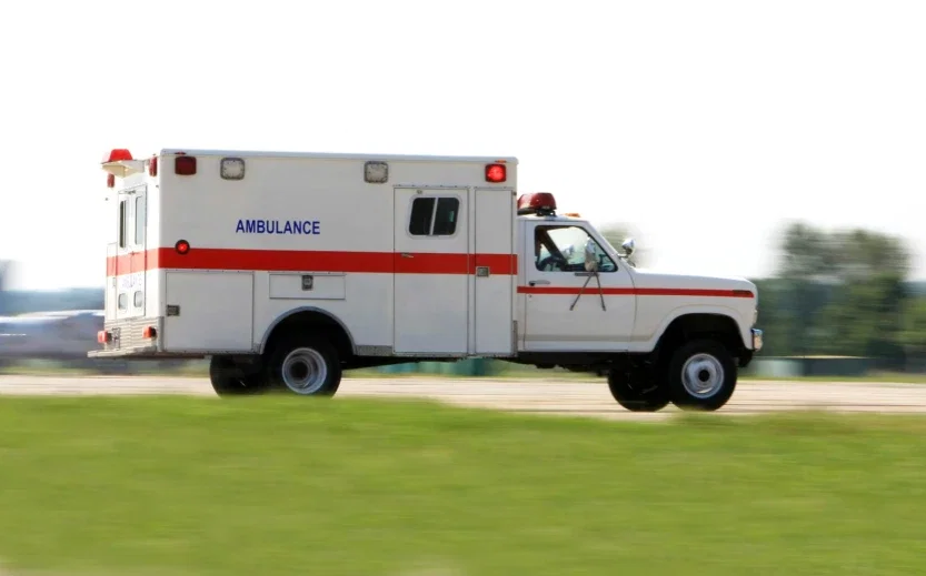 Ambulance speeding along a road with lights activated responding to a personal injury emergency