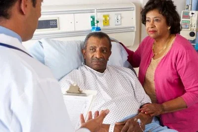 Physician discussing serious medical diagnosis with elderly patient and family member in a hospital room
