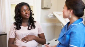 Pregnant woman consulting with a nurse during prenatal appointment related to birth injury and obstetric care