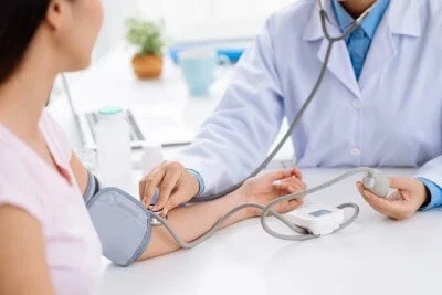 Doctor checking patient blood pressure during medical examination for injury assessment
