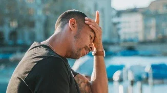 Distressed man holding head in hands outdoors representing emotional suffering in personal injury claim