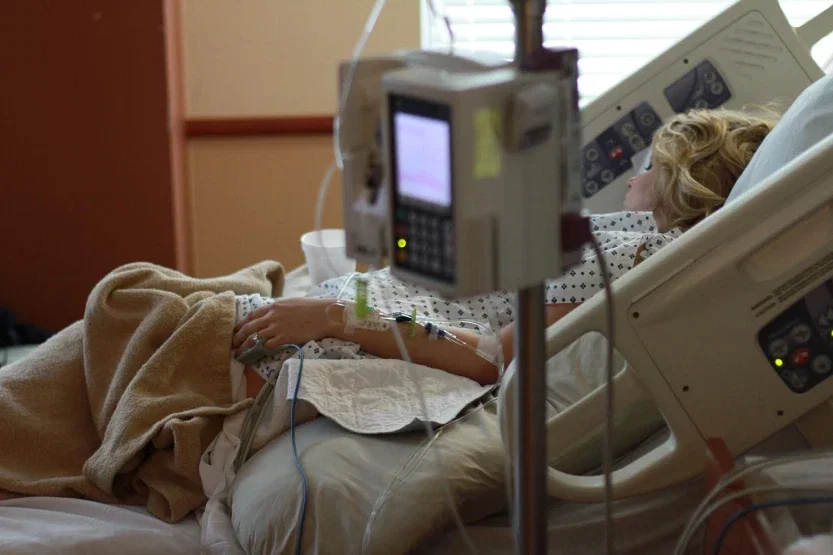 Woman in hospital bed connected to IV monitor during complicated labor and delivery complication