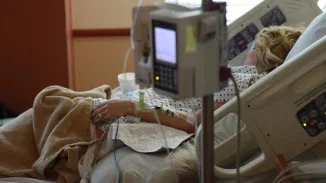 Woman in hospital bed connected to IV monitor during complicated labor and delivery complication