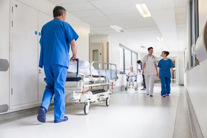 Hospital staff transporting patient on gurney through busy medical corridor in negligence injury case