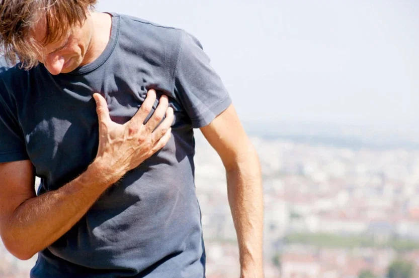 Man clutching chest outdoors representing heart attack risk linked to testosterone therapy injury claim