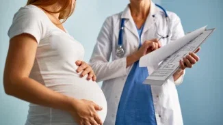 Pregnant woman reviewing medical paperwork with OB-GYN during prenatal care appointment
