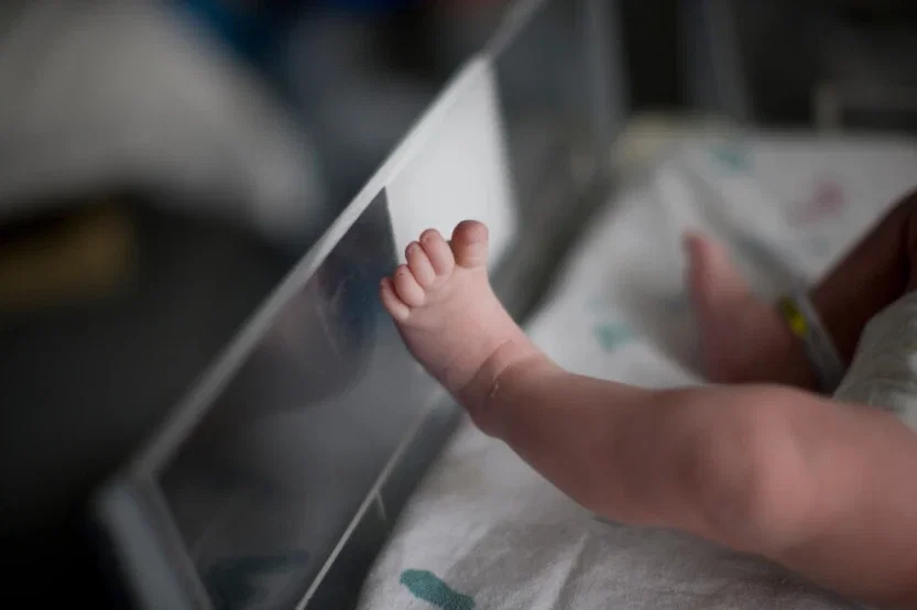 Newborn baby foot resting against hospital bassinet side in birth injury and malpractice case