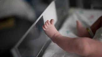 Newborn baby foot resting against hospital bassinet side in birth injury and malpractice case