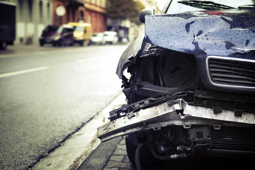 Severely damaged car front end on city street after serious personal injury accident