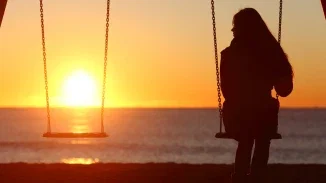 Lone woman sitting on swing at sunset grieving loss after wrongful death or birth injury