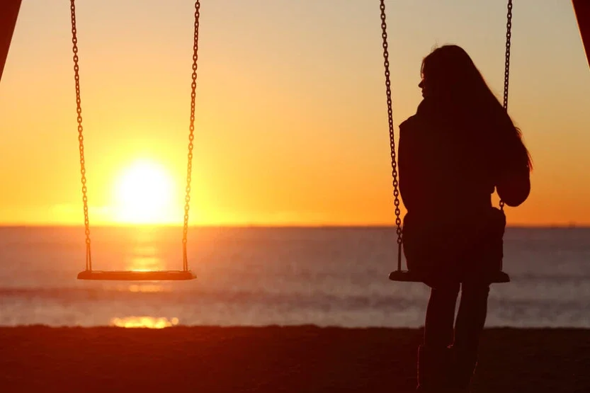 Lone woman sitting on swing at sunset grieving loss after wrongful death or birth injury