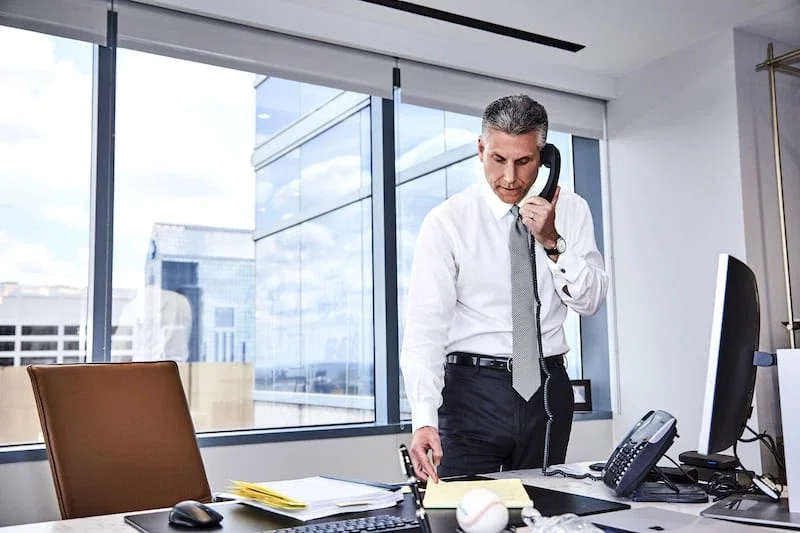 Joel Feller, wrongful death attorney, on phone while reviewing case documents at office desk