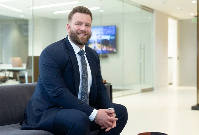 Personal injury attorney Kevin McHale smiling in law firm lobby in navy suit with patterned tie