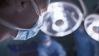 Close-up of surgeon in surgical mask under bright operating room lights during medical malpractice case procedure