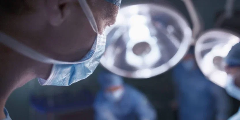 Close-up of surgeon in surgical mask under bright operating room lights during medical malpractice case procedure