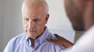 Doctor placing reassuring hand on distressed older patient