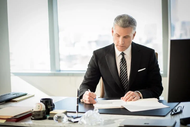 Philadelphia personal injury attorney in dark suit reviewing case documents at desk in high-rise office