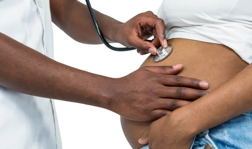 Doctor using stethoscope to examine pregnant patient