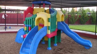 Colorful plastic playground equipment with slides under shade canopy representing premises liability and child injury claims