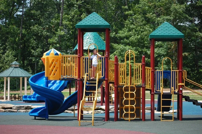 Child waving from colorful playground structure with spiral slide representing premises liability and playground injury claims