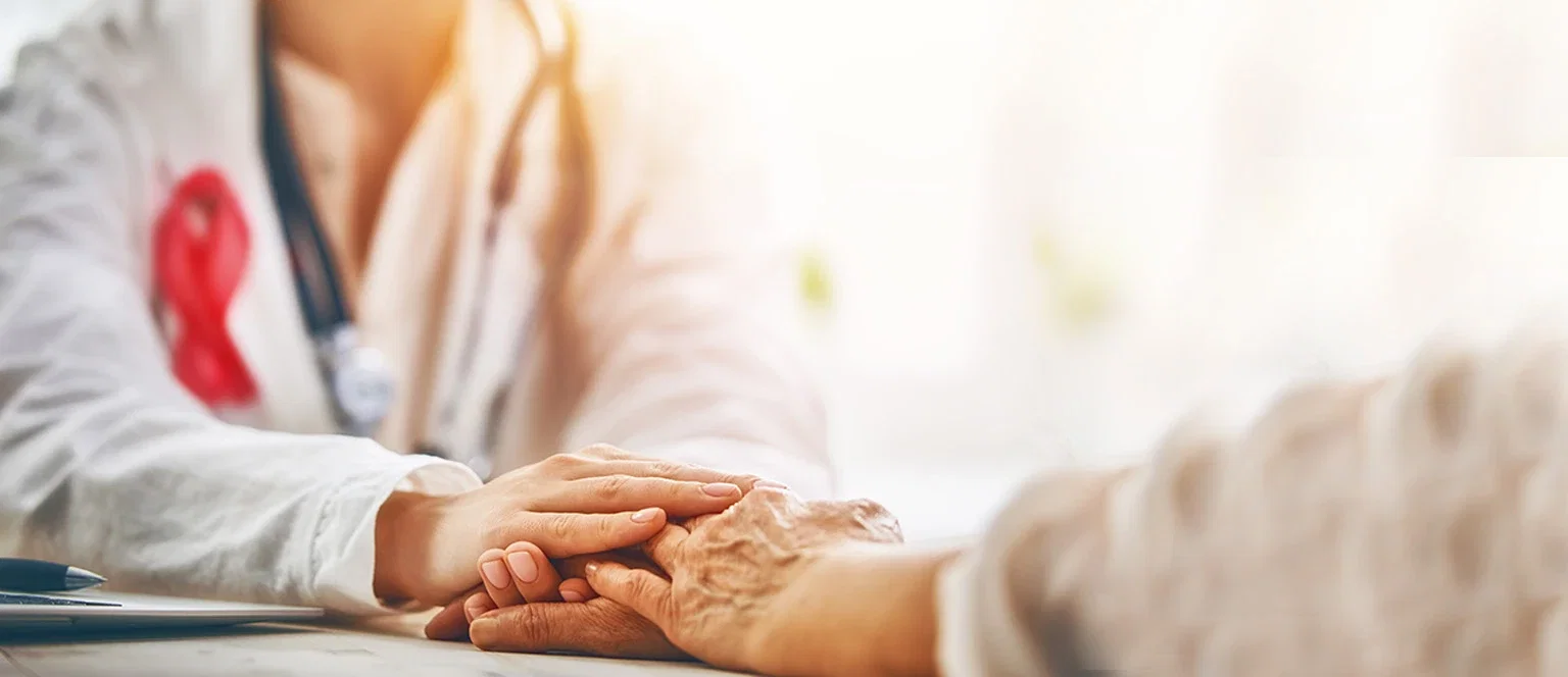 Doctor with cancer awareness ribbon holding an elderly patient