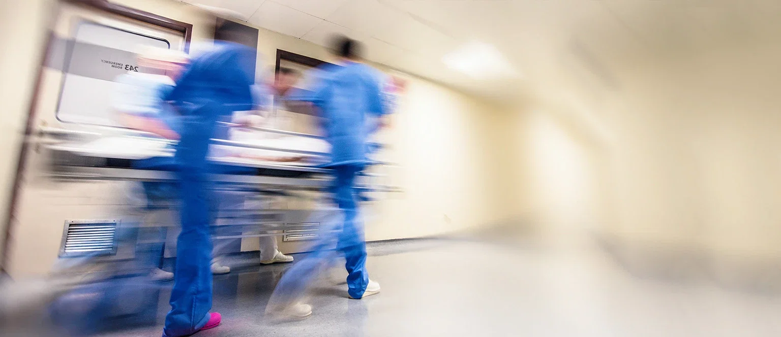 Medical staff in scrubs rushing a patient on a gurney through a hospital corridor for negligence claims