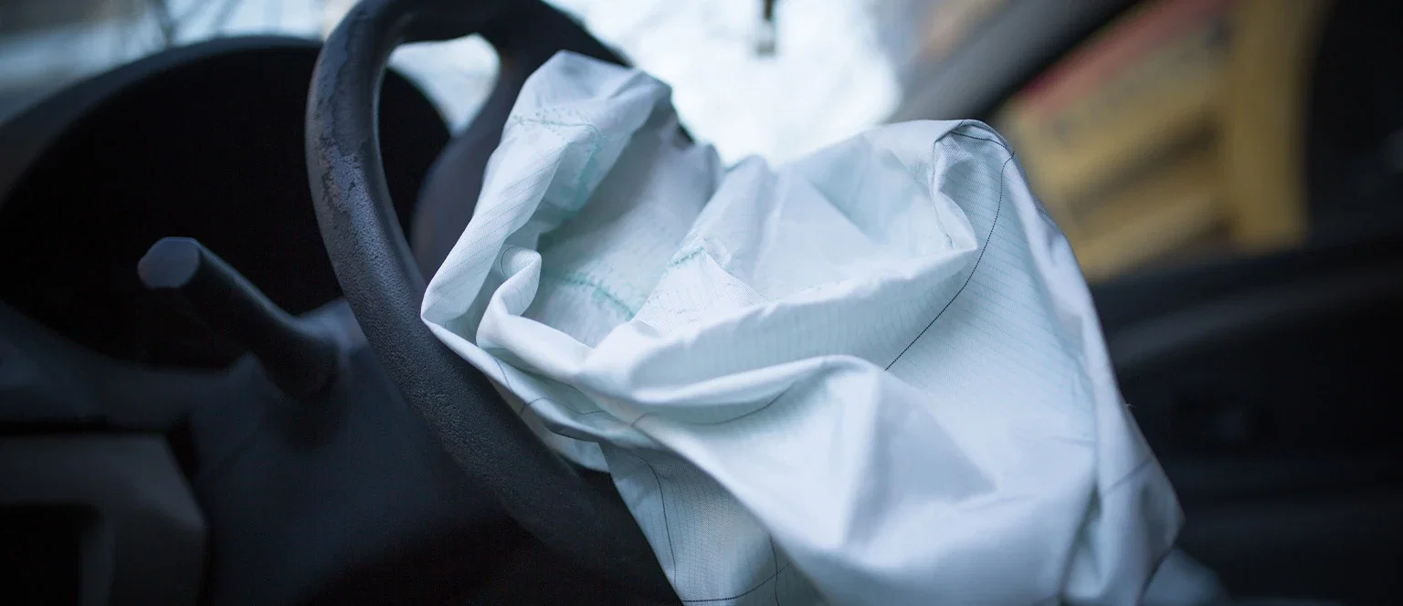 A deflated airbag draped over a car