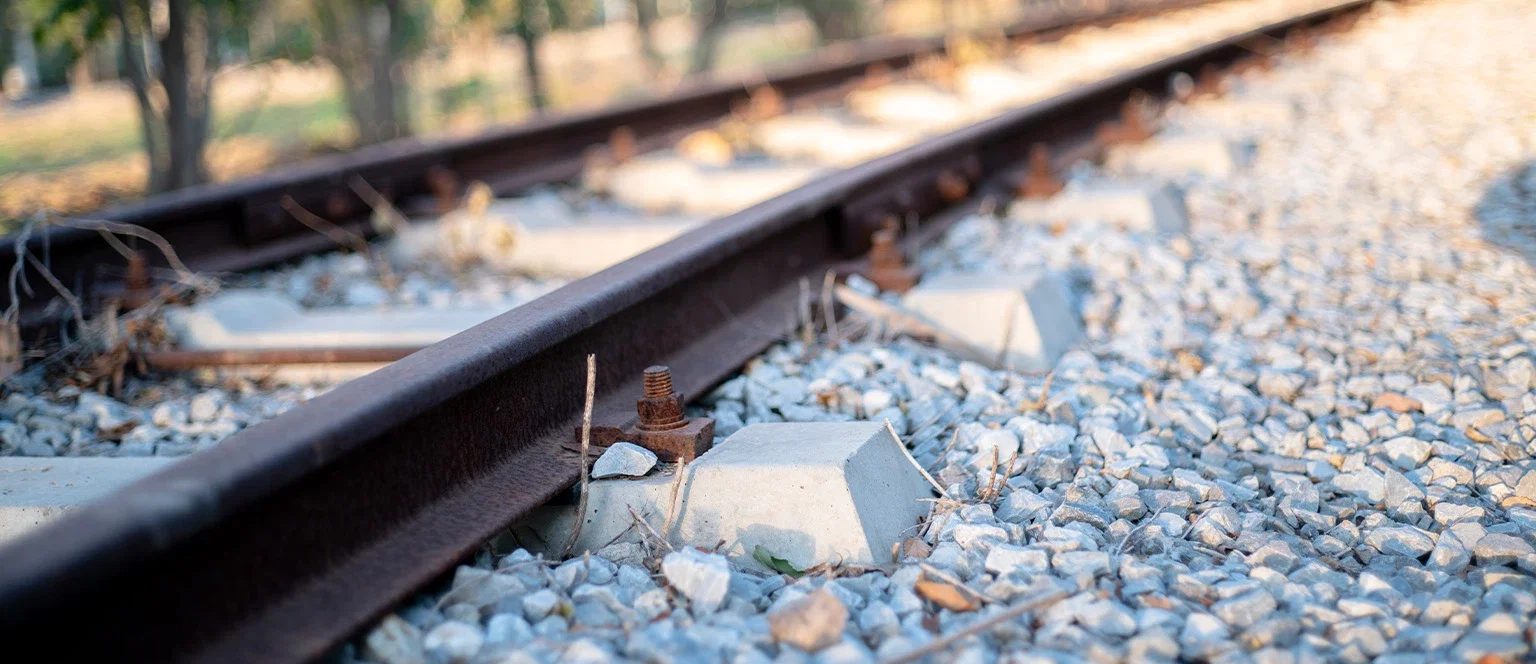 Close-up of rusty railroad tracks and gravel ballast representing FELA railroad accident injury claims