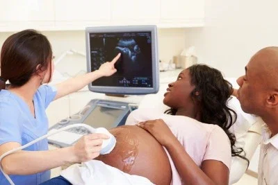 Pregnant woman and partner receiving ultrasound examination from technician representing prenatal medical malpractice birth injury context