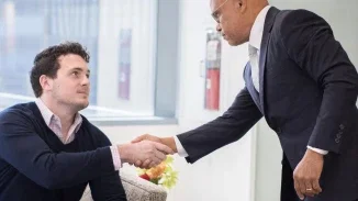 Personal injury attorney greeting client with handshake in modern Philadelphia law firm reception area