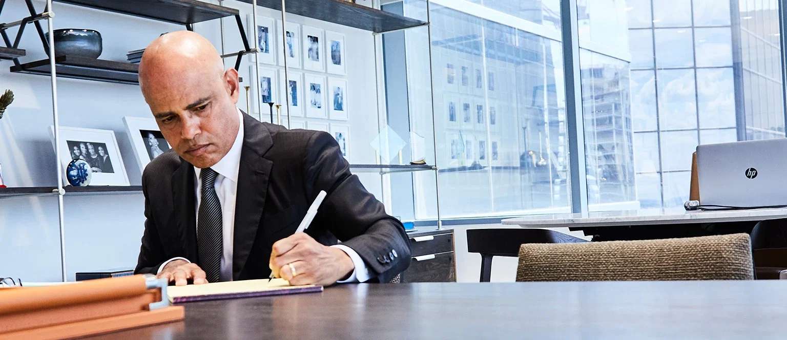 Personal injury attorney in a dark suit writing notes at a conference table in a modern law office