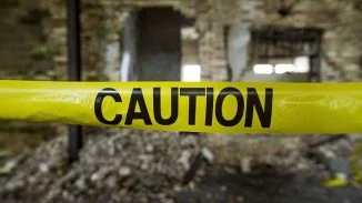 Yellow caution tape stretched across damaged building entrance representing accident hazard and premises liability