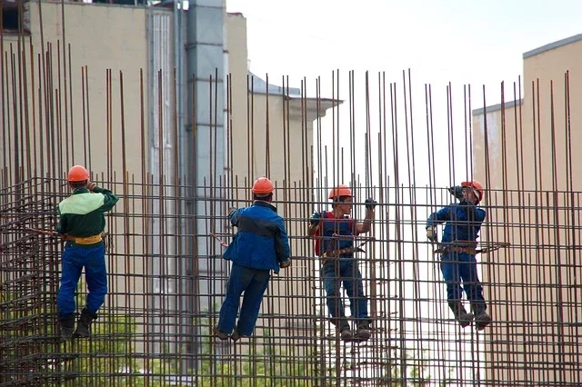 Construction workers in hard hats assembling steel rebar framework on a worksite injury claim