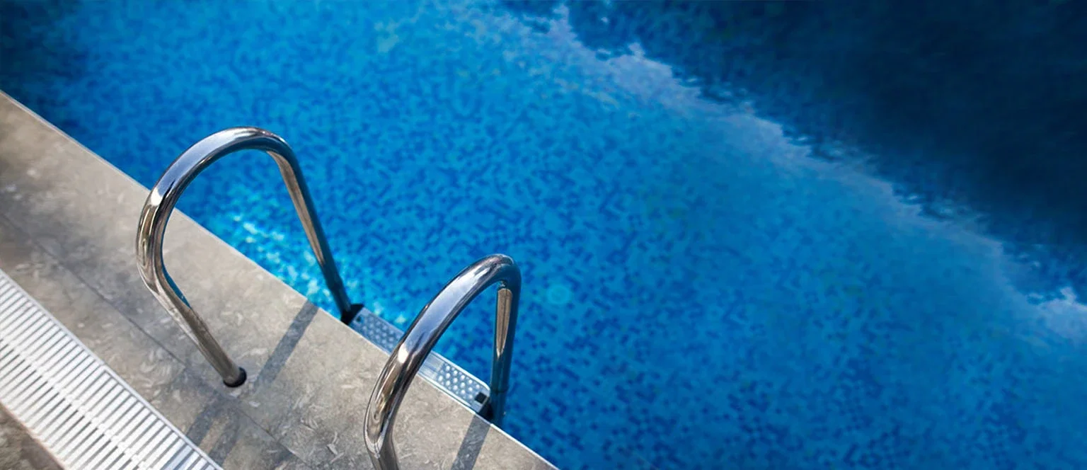 Swimming pool entry ladder and drain grate along the edge representing premises liability and drowning claims